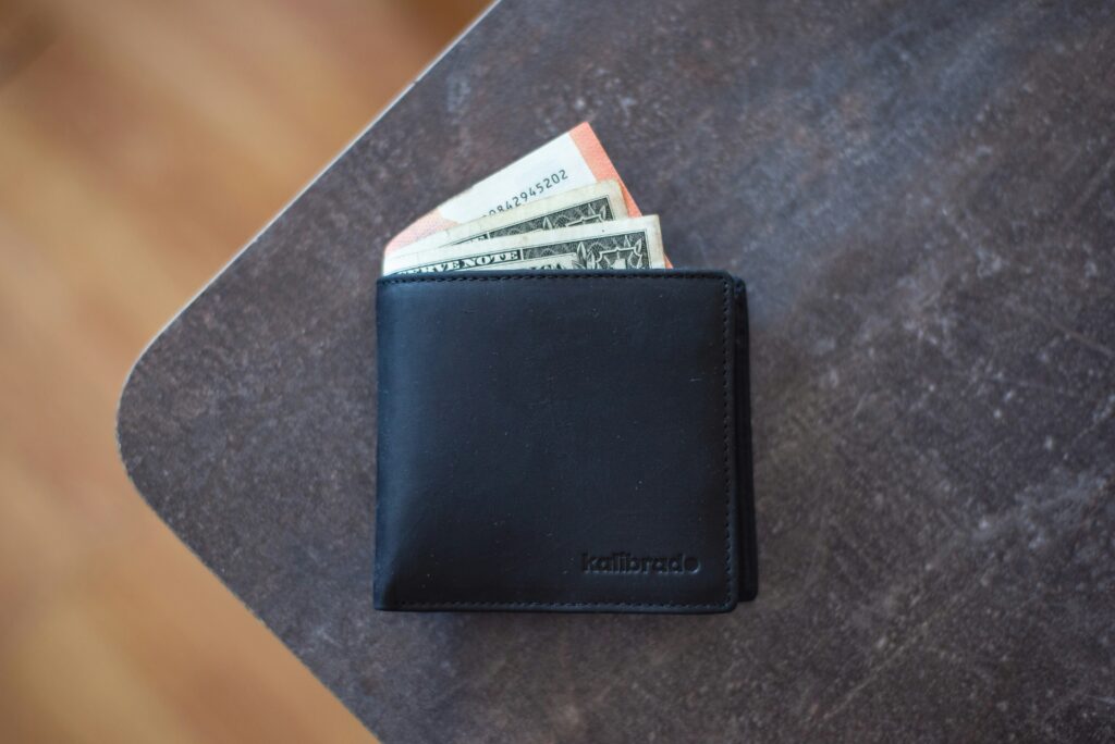 an image of a wallet on a table with a receipt and money sticking out